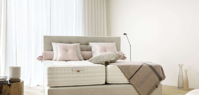 Boxspringbett mit gepolstertem Kopfteil in einem hellen Raum