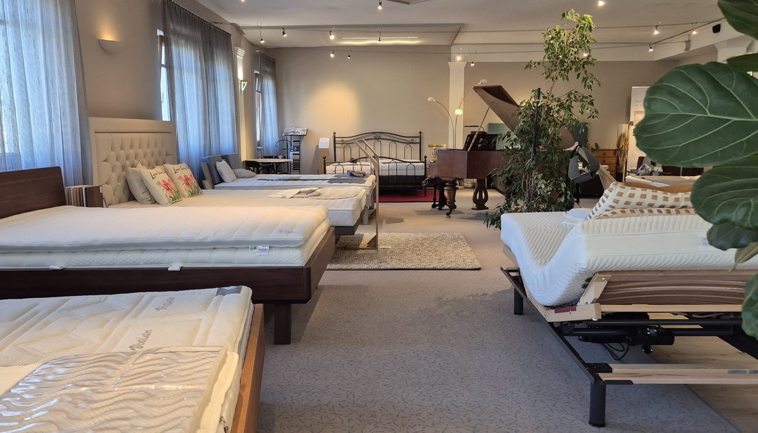 Blick durch das Obergeschoß des Showrooms: Betten und Matratzen in einer Reihe, Tageslicht von den Fenstern